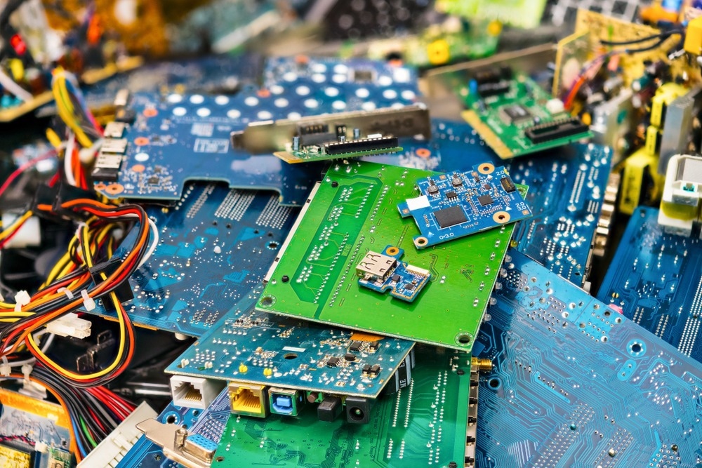 E-waste heap from discarded laptop parts. Connectors, PCB, notebook cards. Colorful blurry background from PC components. Idea of electronics industry, eco, sorting and disposal of electronic waste.