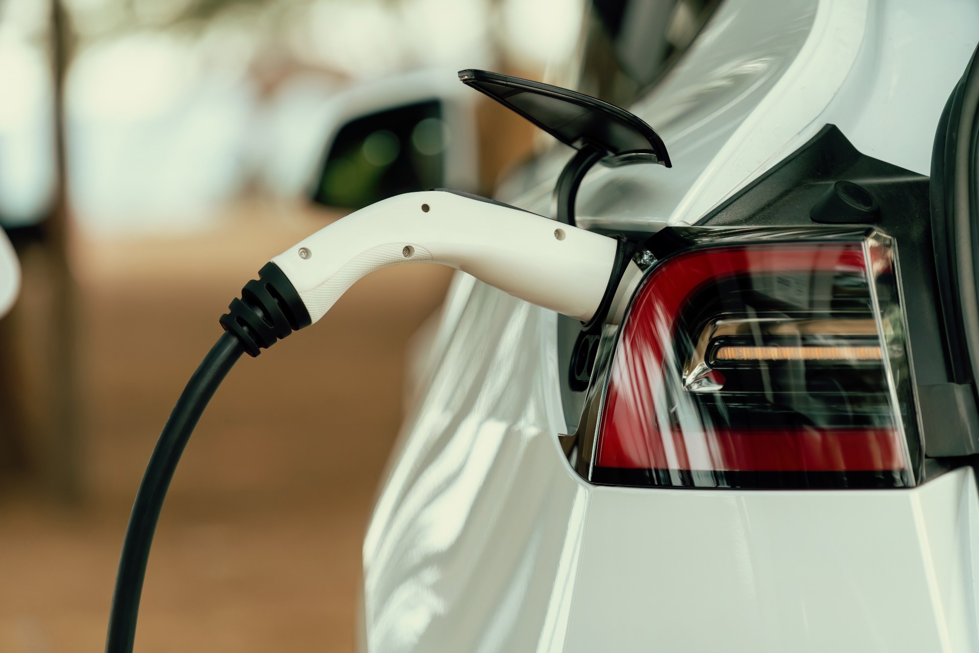 Closeup EV charger handle plugged in or connect to electric car, recharging EV car battery with alternative and sustainable energy with zero CO2 emission for clean environment.