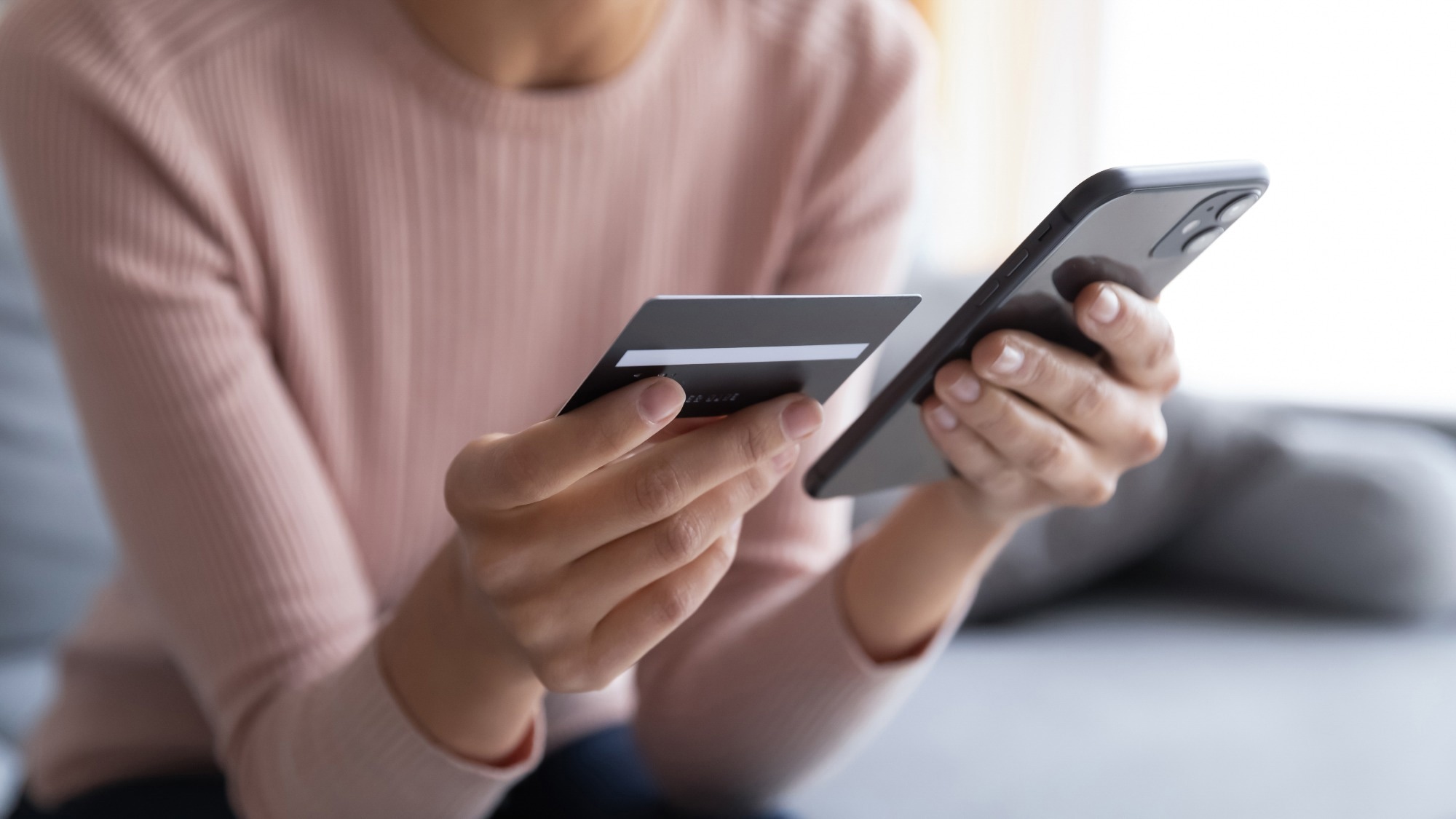 Close up female hands holding credit card and smartphone.