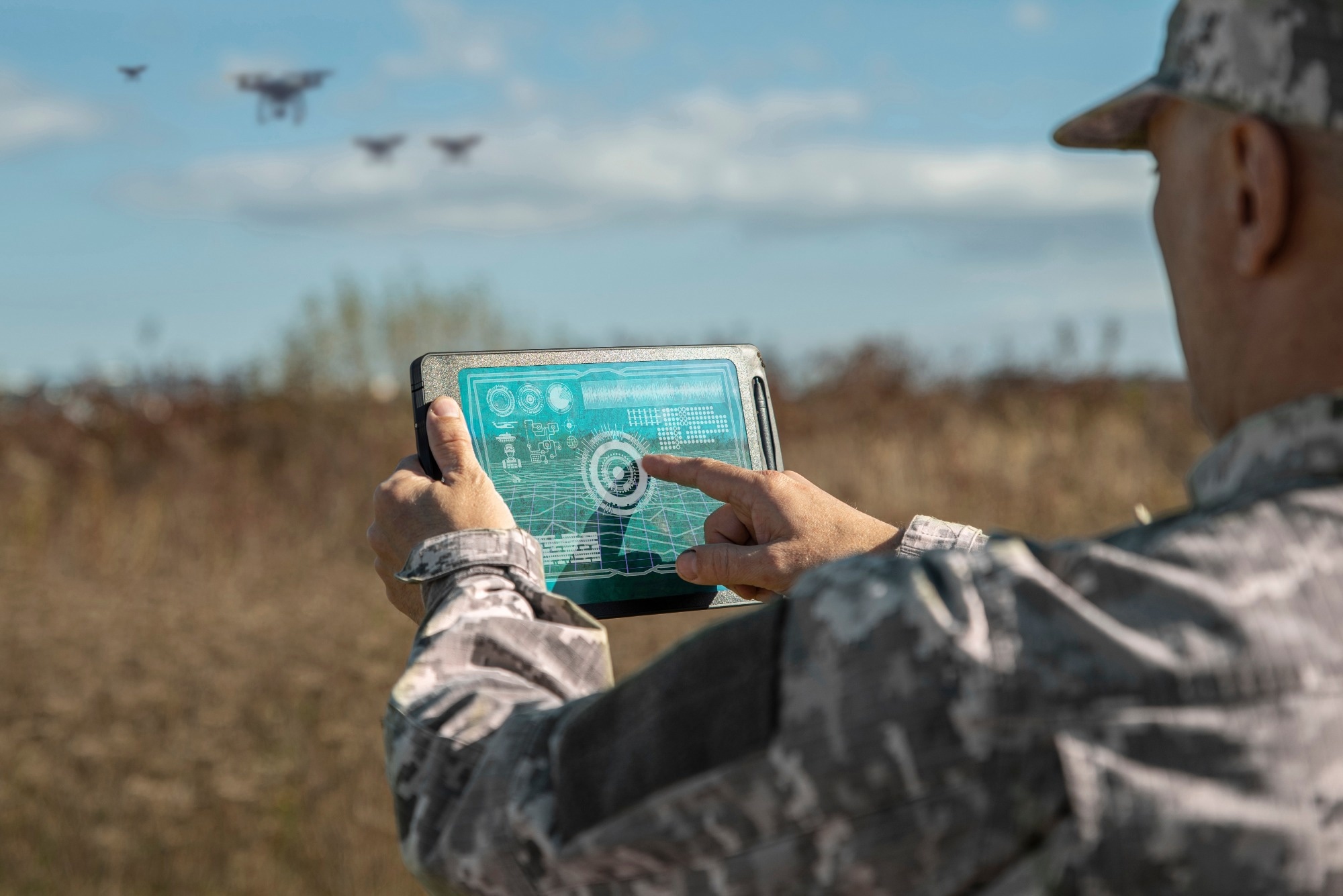 Military commander with a digital tablet device with augmented reality operating drones outdoors.