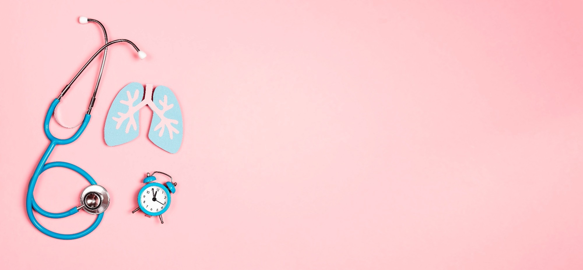 Lung symbol, stethoscope and alarm clock on a pink background. Healthcare and medicine concept.