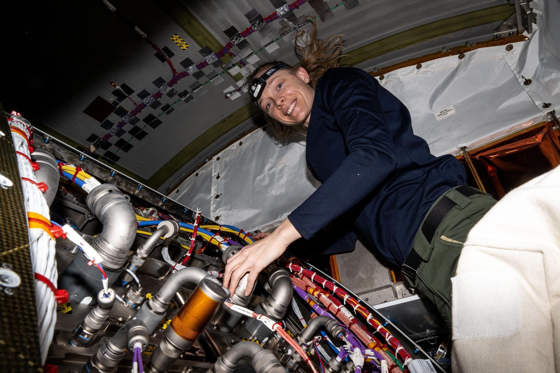 NASA astronaut Nichole Ayers works inside the International Space Station’s Tranquility module, swapping out a remote power controller module and inspecting components on the Avionics Rack.