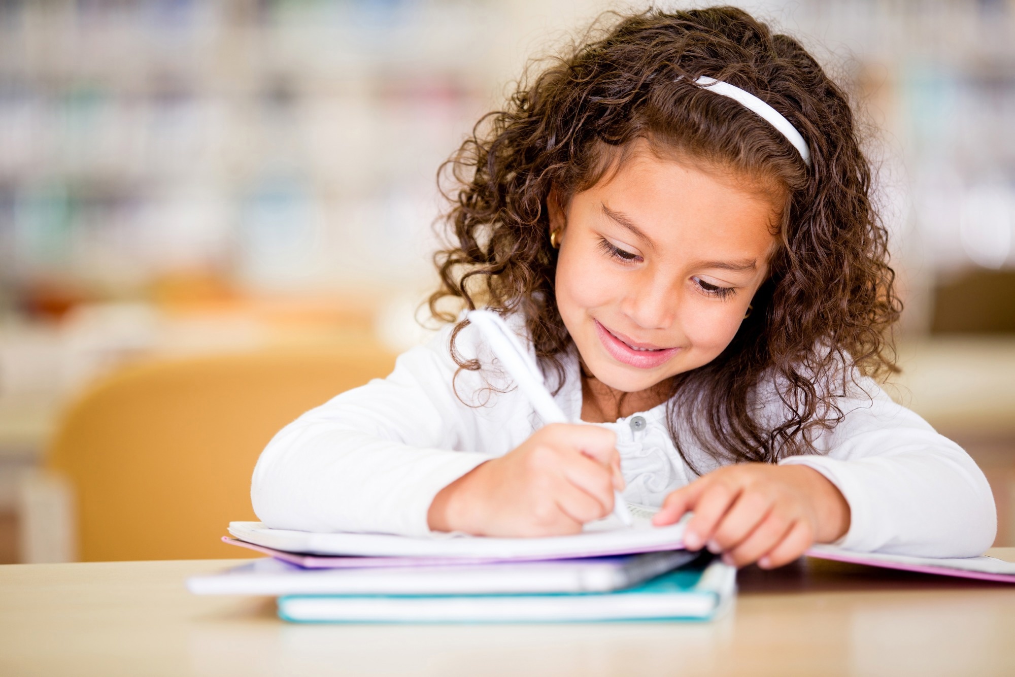 Girl writing in notebook at school looking very happy.