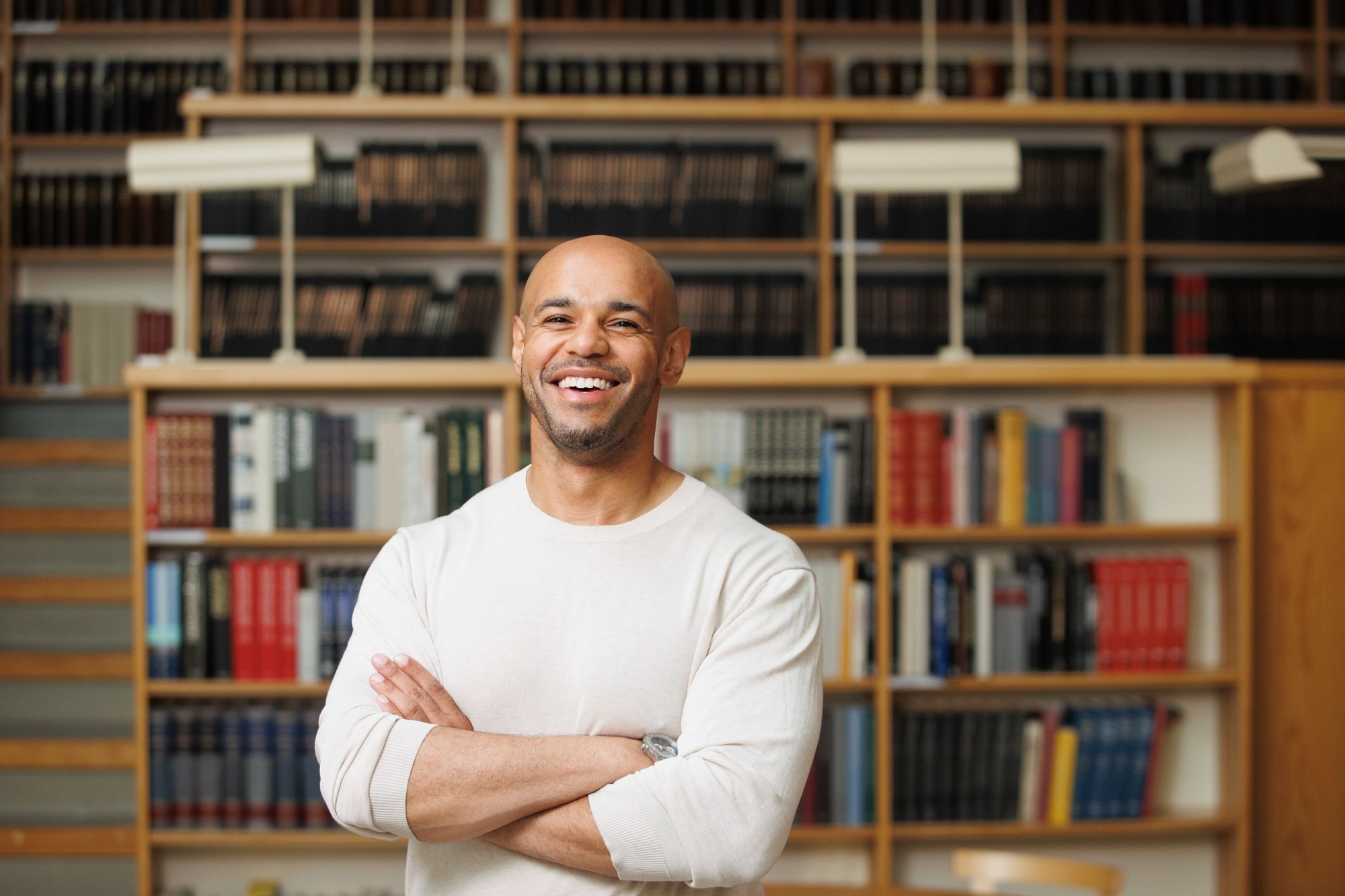 Dr. Andrew Danso standing in front of a book case smiling widely.