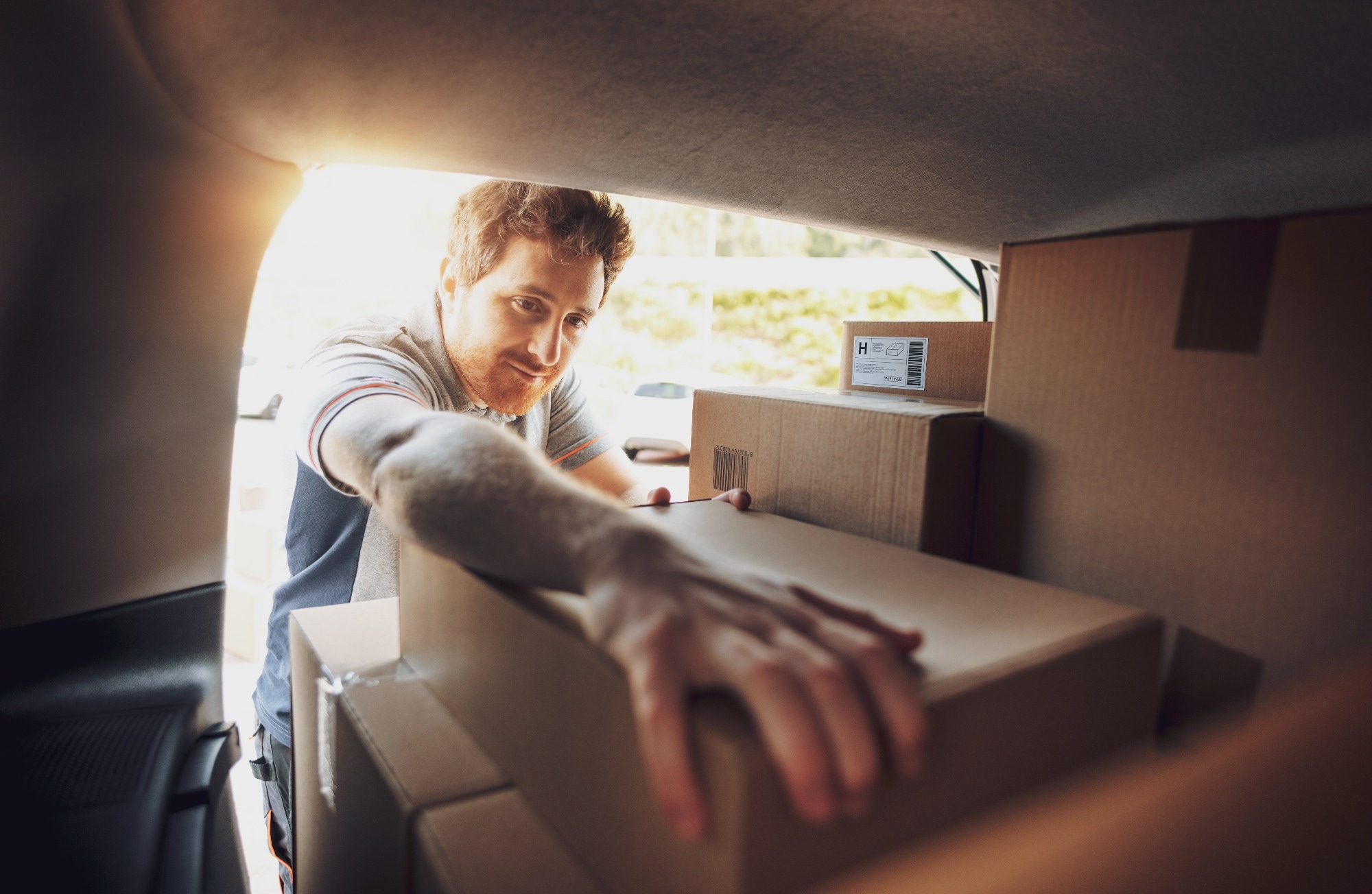 Professional delivery man loading packages into a van.