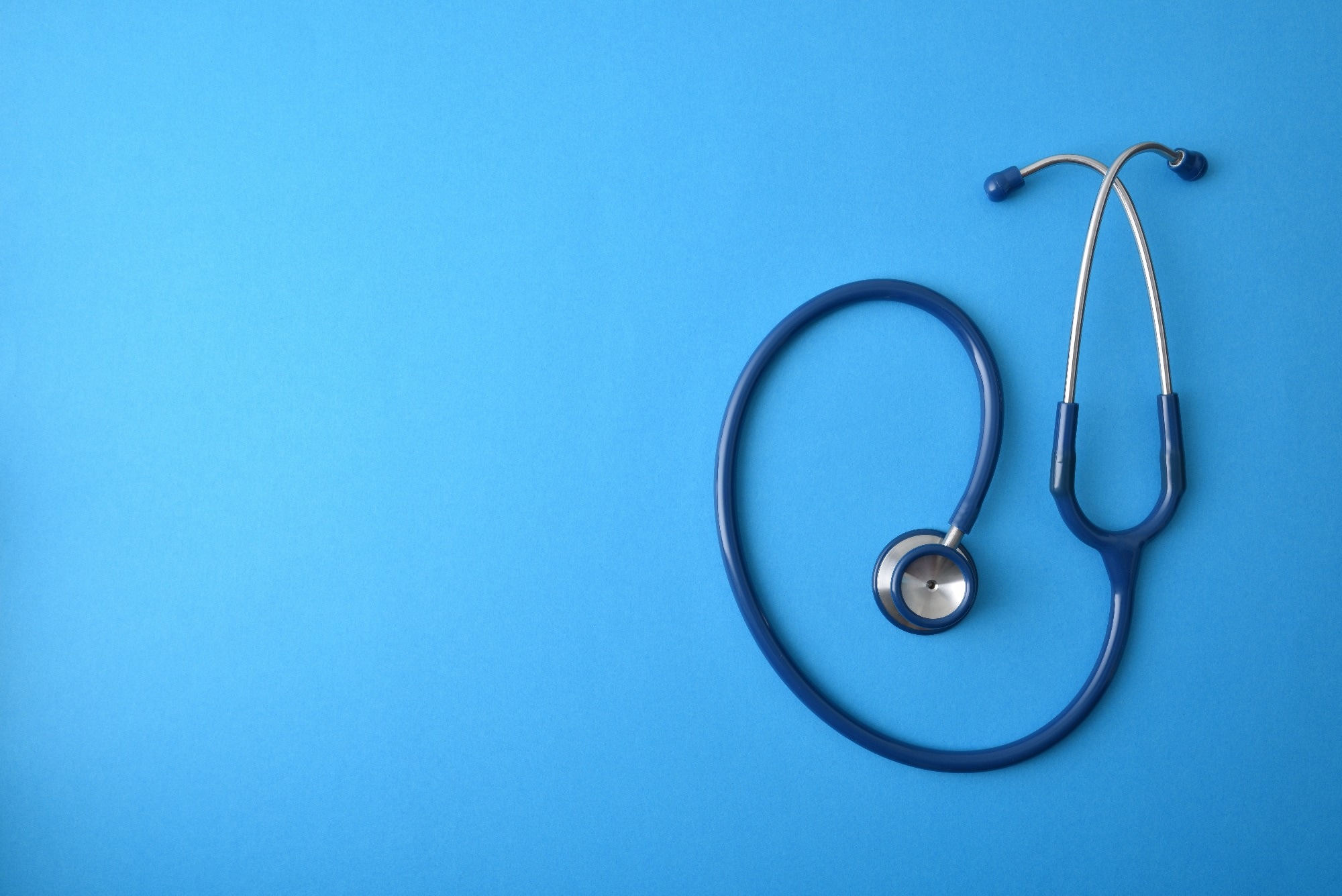 Generic health background with stethoscope isolated on blue background. Top view