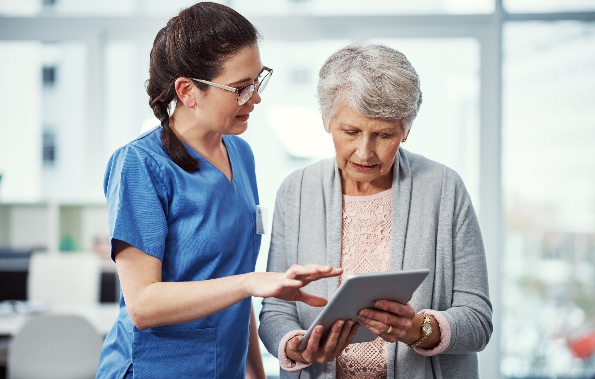 Elderly woman reading off a tablet screen with a nurse